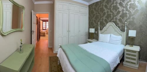 Quarto elegante na Casa Da Avó Ilda com cama queen, papel de parede adamascado, guarda-roupas brancos e vista para o jardim em Matosinhos