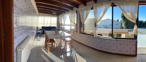 Sala de jantar ensolarada com vista para o oceano na Casa Da Avó Ilda, casa de hóspedes em Matosinhos, com mesa, cadeiras e janelas para o terraço