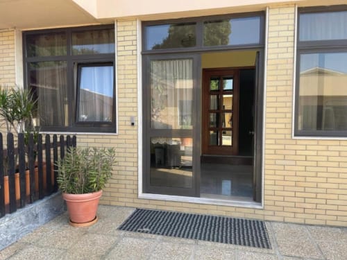 Entrada moderna do pátio da Casa Da Avó Ilda em Matosinhos com portas de vidro, planta em vaso e piso revestido