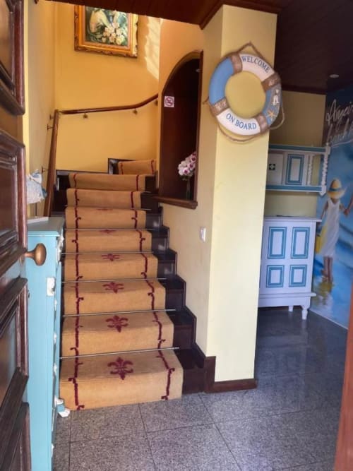 Escada com tapete decorativo levando ao andar superior da pousada Casa Da Avó Ilda em Matosinhos com decoração náutica