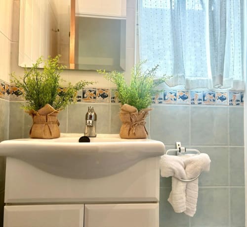 Moderno lavamanos con plantas en macetas, espejo, toallas y ventana con vistas al mar en el apartamento Holibai de Baiona