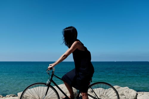 Woman on bicycle overlooking turquoise sea at Bombarral, Óbidos – Home Alliance B&B Portugal
