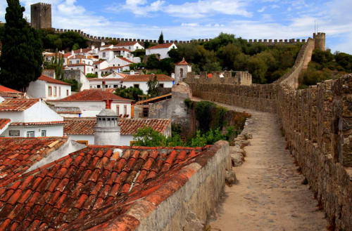 Medieval castle walls and white village houses with red tile roofs in Óbidos, Portugal