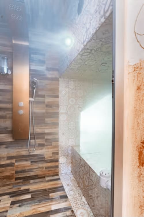 Moderna spa bathroom nella wellness room CasaRosada di Vidracco con doccia a pioggia, pavimentazione in legno e piastrelle decorative