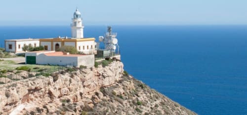 Faro del Hostal Juan Carlos sobre acantilados rocosos con vistas al turquesas Mar Mediterráneo en Carboneras, España