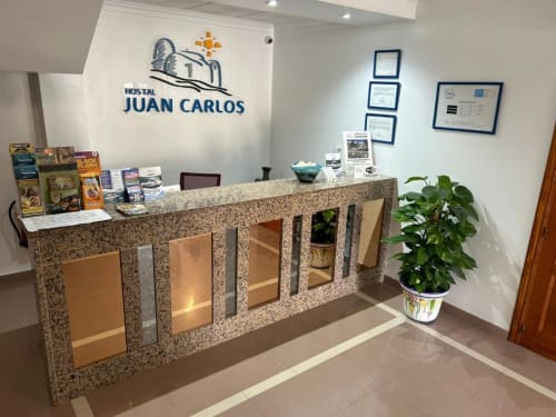 Mostrador de recepción del Hostal Juan Carlos en Carboneras con encimera de granito, materiales informativos y decoración con planta verde