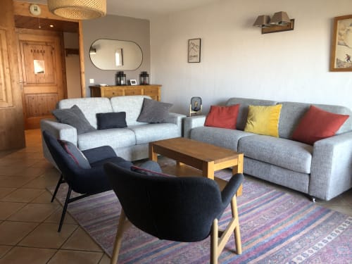 Modern living room of the CosyArc Saint-Bernard apartment in Arc 1800 with gray sofas, wooden coffee table, and colorful cushion