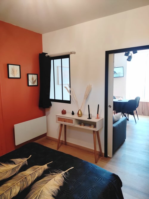 Chambre moderne à Accolade Châteaudun avec mur d'accent rouge, coiffeuse et accès à la vue sur la ville