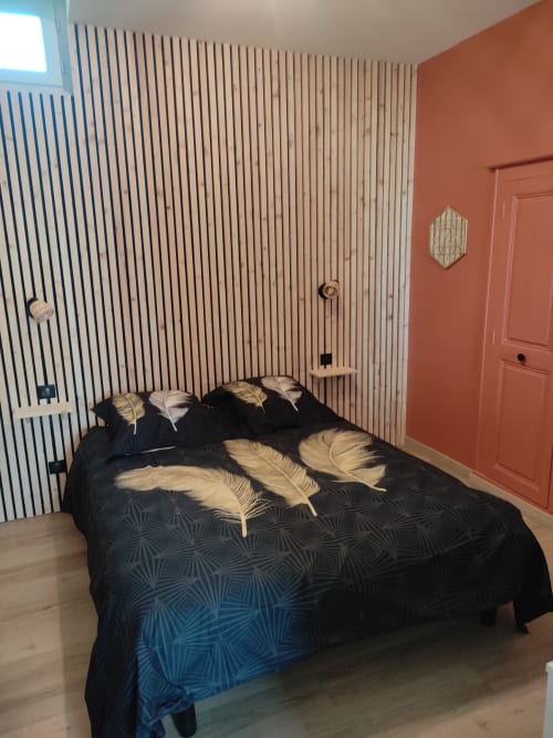 Chambre moderne de l'appartement Accolade à Châteaudun avec mur à rayures, literie noire et porte corail