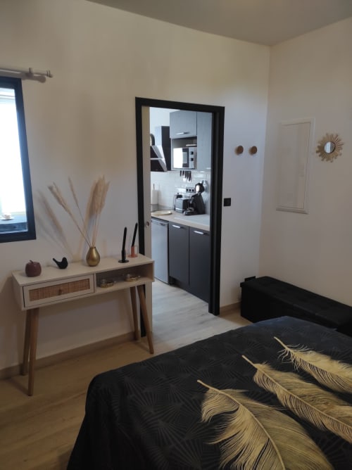 Chambre moderne avec vue sur la ville à l'Accolade Châteaudun, lit, bureau de coiffeuse et cuisine ouverte