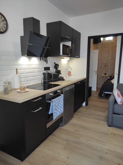 Cuisine moderne noire avec comptoir en bois dans l'appartement Accolade, Châteaudun