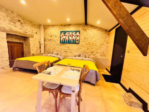 Chambre lumineuse à Vue Sur Gindou à Gindou avec deux lits jaunes, table à manger et murs en pierre