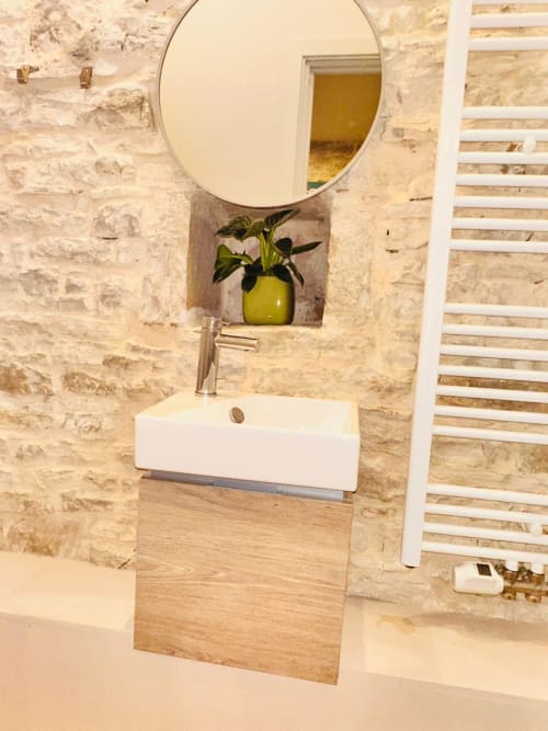 Lavabo moderne avec vanité en bois, miroir rond et plante en pot à Vue Sur Gindou à Gindou, France