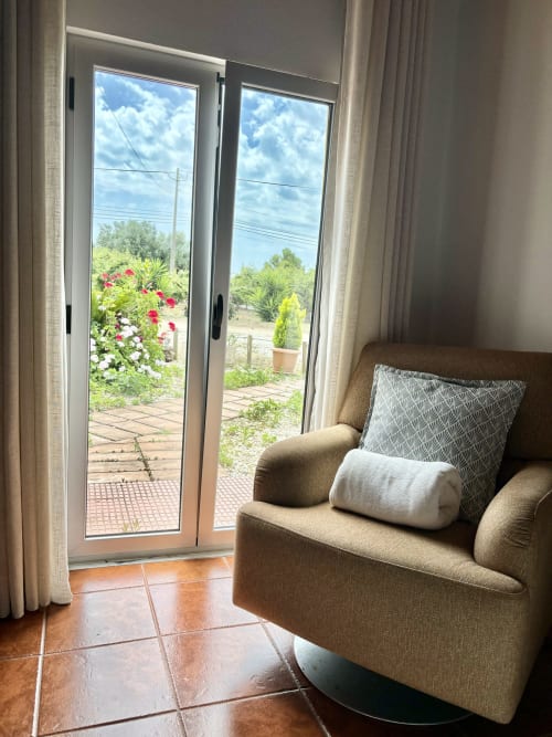 Acomodação aconchegante no Quarto Double Superior da Home Alliance B&B, Bombarral, com poltrona e portas de varanda voltadas para o jardim