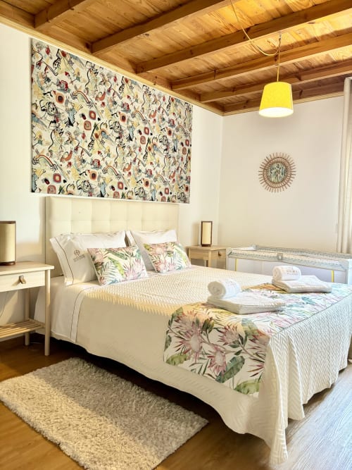 Bright bedroom at Home Alliance B&B in Bombarral with cream quilted bed, patterned headboard artwork, wooden ceiling beams,