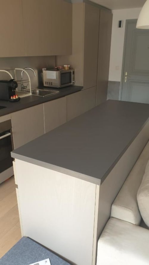 Cuisine moderne à Duplex les Myrtilles Les Carroz avec meubles blancs, plans de travail foncés et îlot central.