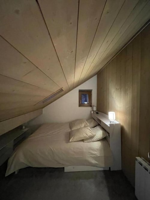 Chambre douillette sous les combles avec plafond en bois mansardé et petite fenêtre à Duplex les Myrtilles Les Carroz, France
