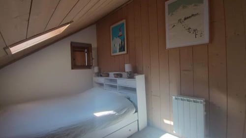 Chambre douillette en loft à Duplex les Myrtilles Les Carroz France avec lit blanc, murs en bois et velux