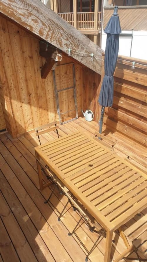 Terrasse en bois avec chaise longue et parasol bleu à Duplex les Myrtilles Les Carroz, France