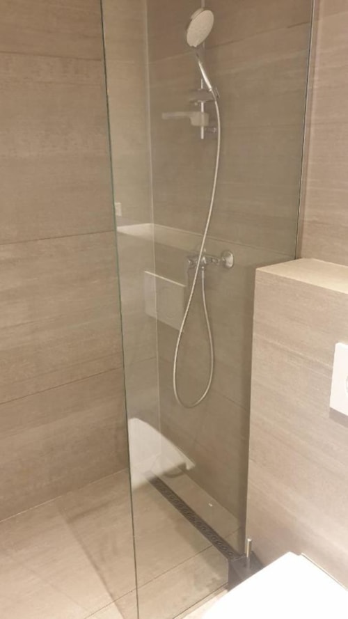 Douche moderne avec parois en verre, pommeau de douche effet pluie et douchette à main dans une salle de bains contemporaine Duplex les Myrtilles Les Carroz