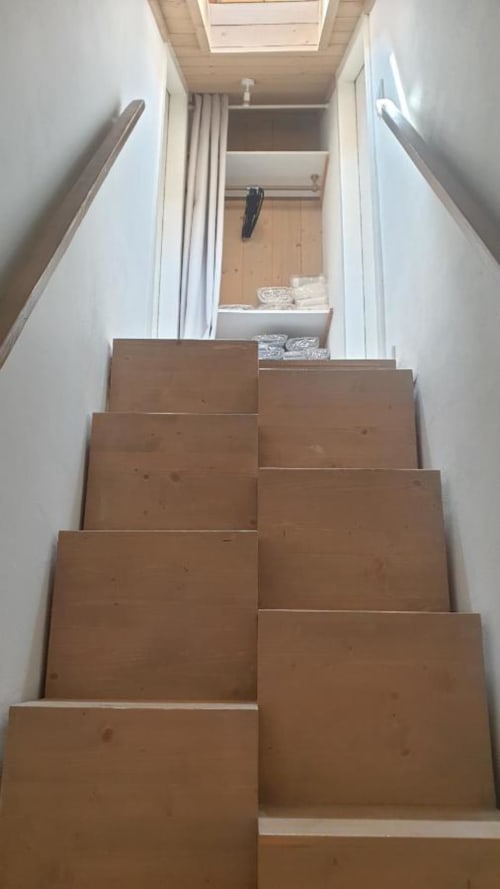 Escalier pas japonnais en bois aux murs blancs et rampes métalliques menant à l'étage supérieur de Duplex les Myrtilles Les Carroz