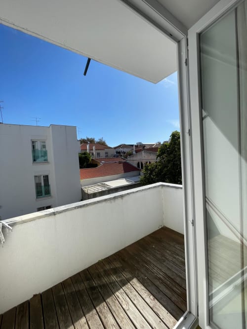 Vista da varanda do apartamento Cascais Houses em Juromenha com deck de madeira sobre edifícios de telhado em terracota e céu limpo