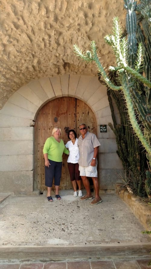Tres huéspedes posan en la entrada arqueada de madera de la casa rural Can Gat Vell en Girona, Empordà-Cataluña, España.