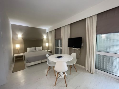 Modern hotel suite at Casas de Juromenha with bed, dining area, TV, and large windows overlooking Juromenha