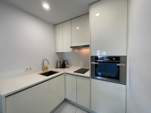Modern white kitchen with stainless steel oven, black cooktop, and sink at Casas de Juromenha, Juromenha