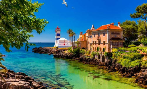 Casas de Juromenha coastal estate with orange-roofed palace, lighthouse, and turquoise waters in Portugal