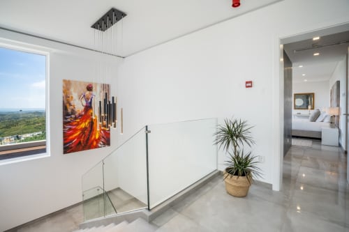 Escada de villa moderna com guarda-corpos de vidro, obras de arte e planta em vaso com vista para o pitoresco Caldas de Monchique