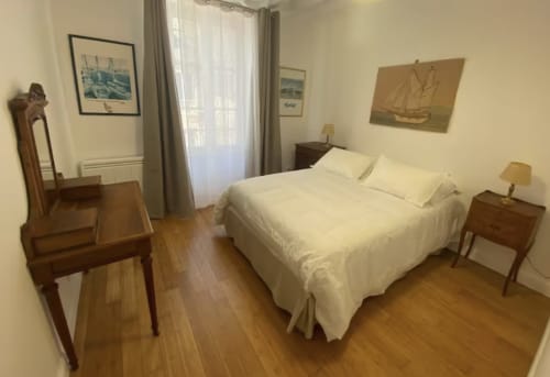 Bright bedroom at Le 58 Bayeux apartment with white bed, wooden furniture, nautical decor, and hardwood floors