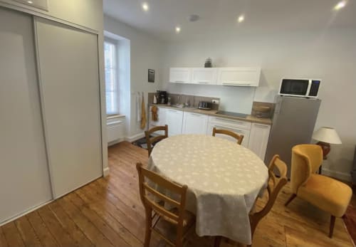 Open-plan kitchen and dining area at Le 58 Bayeux apartment in Bayeux with white cabinetry, dining table, and modern