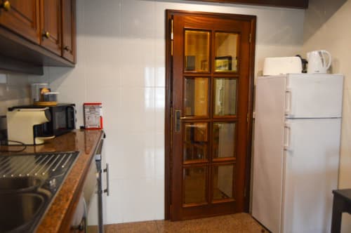 Cozinha da villa Casa Da Avó Ilda em Matosinhos com porta de madeira, refrigerador e eletrodomésticos de cozimento
