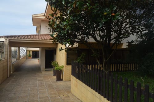 Entrada da villa Casa Da Avó Ilda em Matosinhos com pátio coberto, terraço de tijolos e vegetação exuberante