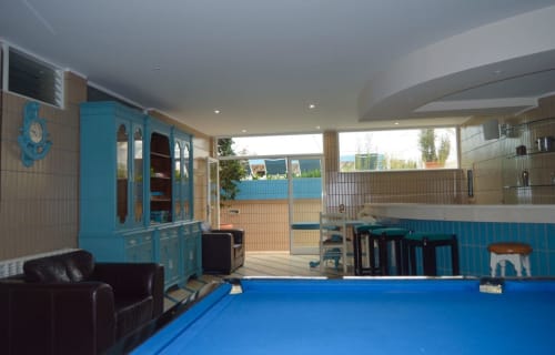 Sala de jogos moderna com mesa de sinuca azul, armários turquesa e área de lounge na Casa Da Avó Ilda, Matosinhos