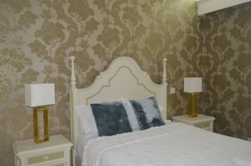Quarto elegante na villa Casa Da Avó Ilda em Matosinhos com papel de parede adamascado, cama creme, almofadas azuis e luminárias douradas