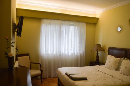 Quarto amarelo vibrante na villa Casa Da Avó Ilda em Matosinhos com cama queen, móveis de madeira escura e luz natural