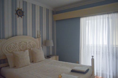 Quarto com tema náutico na villa Casa Da Avó Ilda em Matosinhos com paredes listradas, relógio em forma de roda de navio e vista para o oceano