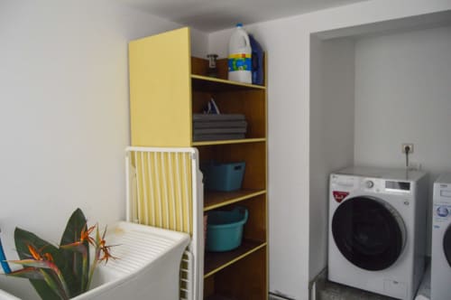 Sala de lavanderia moderna na villa Casa Da Avó Ilda em Matosinhos com prateleiras de armazenamento e máquina de lavar