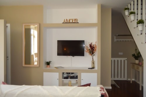 Apartamento moderno com 2 quartos em Matosinhos, com TV de parede, móveis em madeira e acesso por escadas ao piso superior