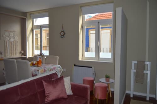 Sala de estar iluminada no apartamento Casa Da Avó Ilda em Matosinhos, com sofá bordô, área de refeições e portas francesas que se abrem para