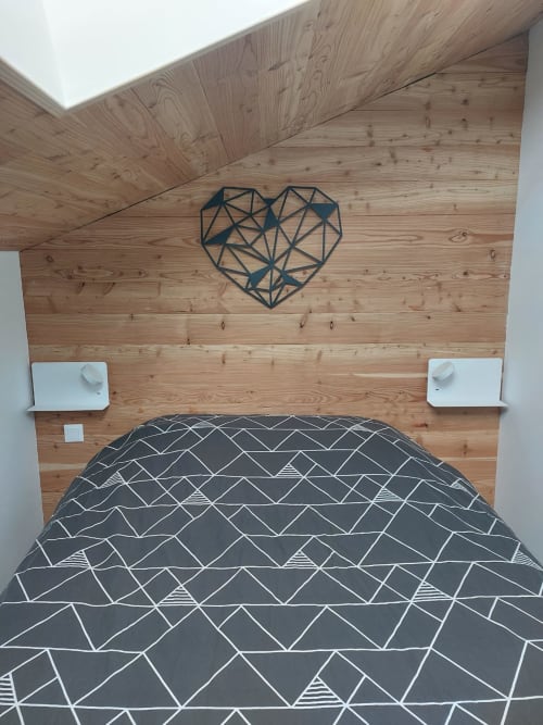 Chambre moderne au CMD Méribel Le Pralin avec murs en bois, art mural cœur géométrique, literie patterned et tables de nuit blanches