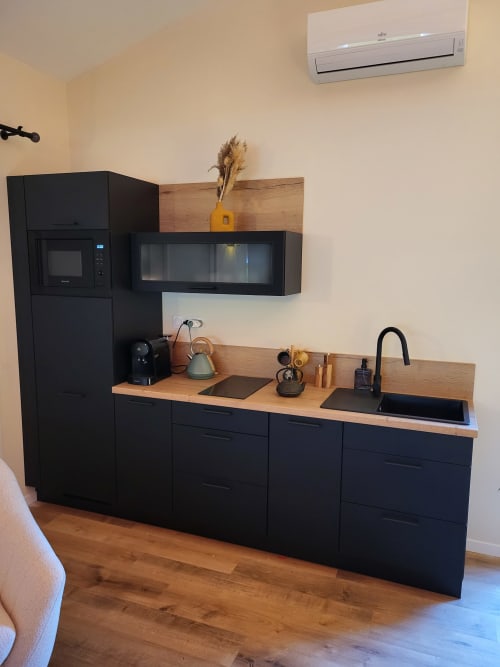 Kitchenette moderne noire avec plan de travail en bois, micro-ondes, évier et plaque de cuisson dans une chambre Suite & Duplex, Cabannes, France