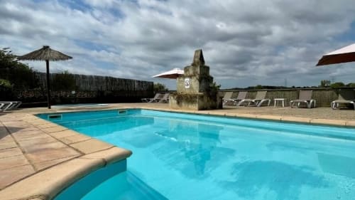 Piscina de aguas cristalinas en Can Gat Vell B&B en Girona, Empordà, con tumbonas y piedra rústica