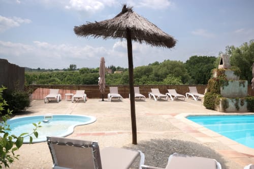 Área de piscina de Can Gat Vell con tumbonas, sombrilla de paja y vistas a la campiña del Empordà en Girona