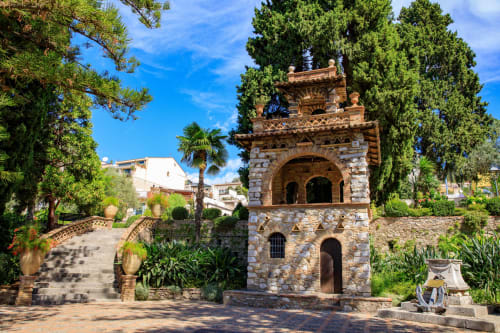 Torre storica in pietra circondata da lussureggianti giardini a Taormina, vicino agli Appartamenti ToviMar