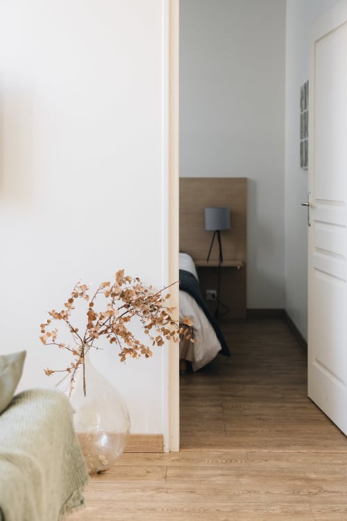 Couloir moderne de la chambre à La Maison D'olivier avec fleurs séchées, plancher en bois et porte ouverte sur la chambre