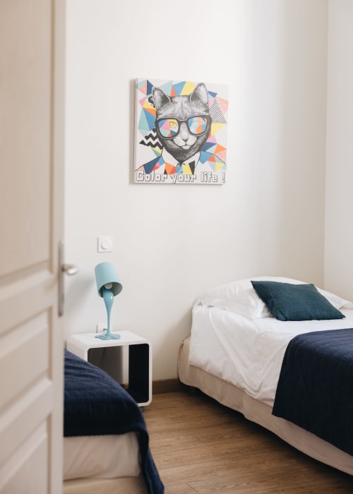 Chambre contemporaine du gîte La Maison D'olivier avec œuvre d'art félin colorée, literie blanche et décoration minimaliste