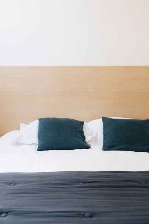 Chambre minimaliste avec coussins bleu-vert et parure de lit blanche à La Maison D'olivier B&B à Mesnard La Barotière